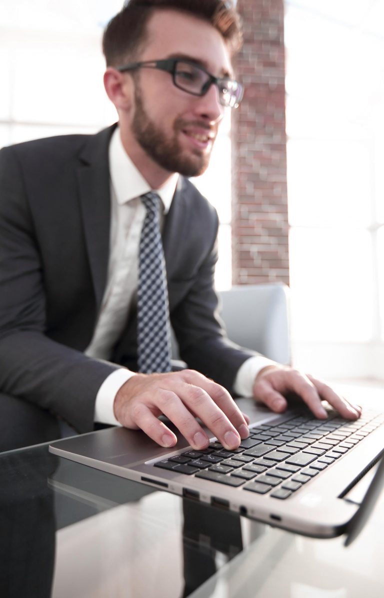 concentrated-young-businessman-is-typing-information-his-laptop-office